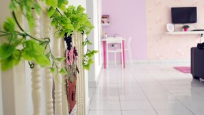 A hallway with a white railing, a pink wall, and a television mounted on the wall. - Manis-Manis Pink Lady Cottage (Malacca City)