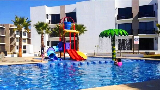 Ein Swimmingpool mit Wasserrutsche und einer Palme.
