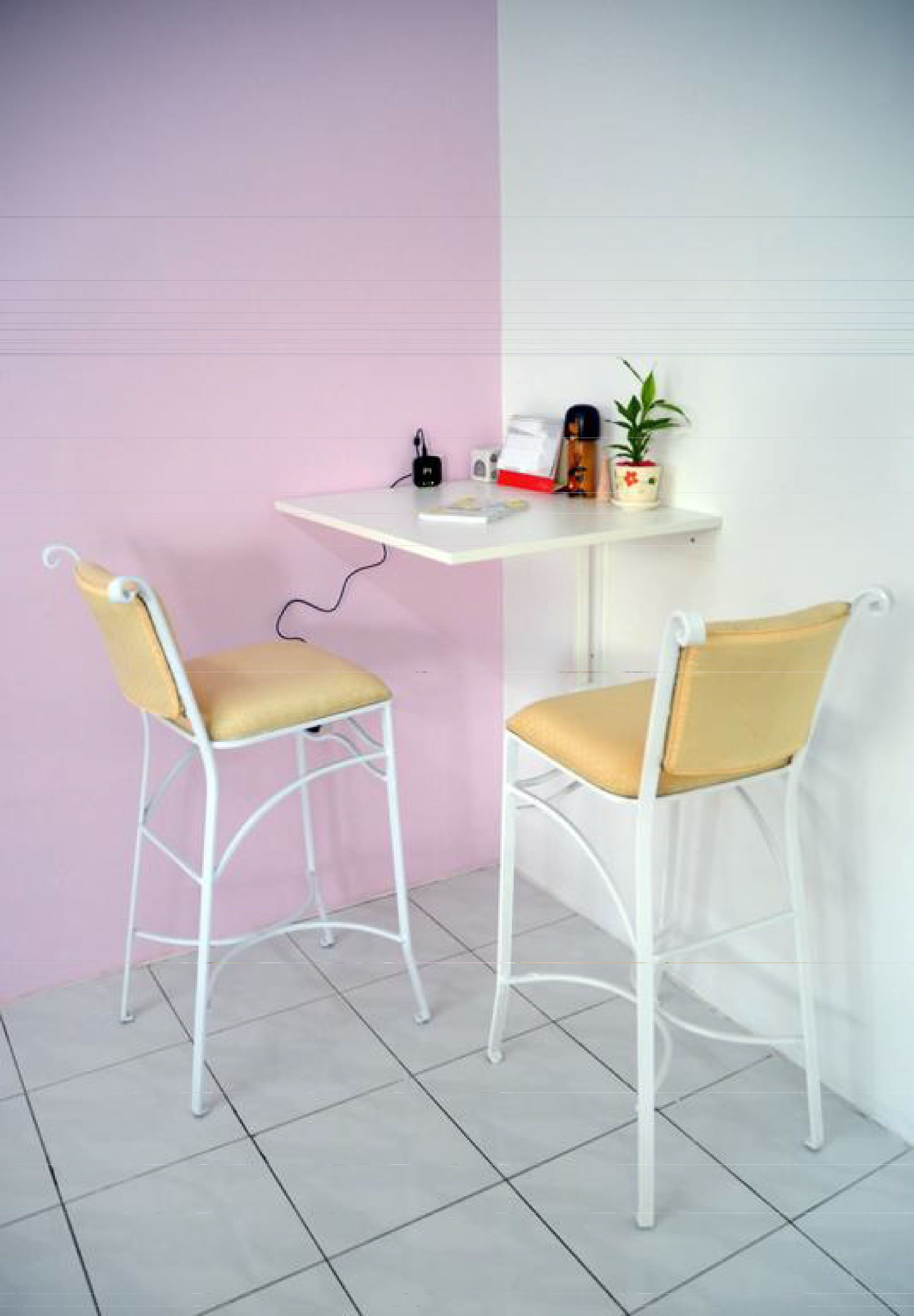 Two white metal chairs with yellow cushions, a white table with a power strip, a small potted plant, and a red and white box.