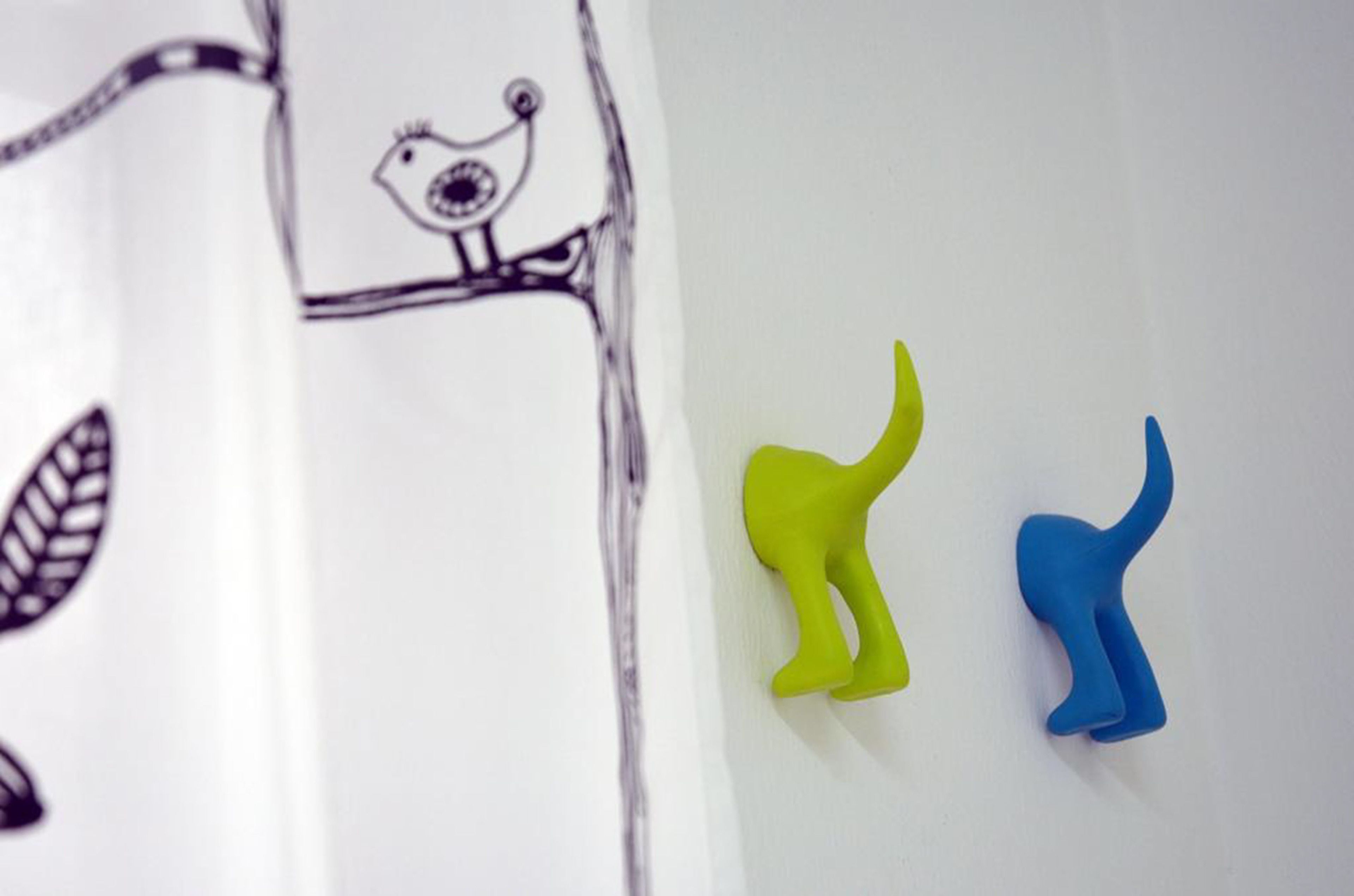 A white wall with a black and white drawing of a bird and two small, colorful, abstract shapes.
