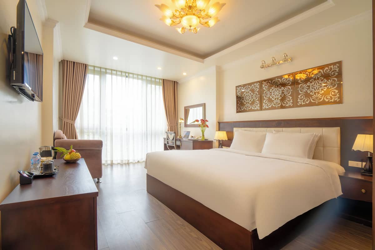 Een hotelkamer met een groot bed, een bureau met een flatscreen televisie, een stoel en een decoratief wandobject.