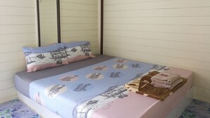 Una cama con un edredón estampado, almohadas y una pila de toallas dobladas.