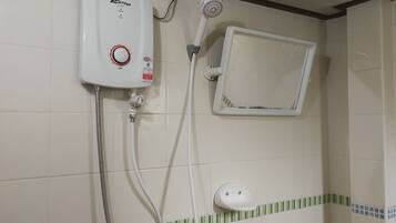 A bathroom with a wall-mounted water heater, a showerhead, and a small window.
