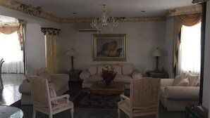 A spacious living room with a chandelier, a sofa set, two armchairs, and a coffee table. - Casa Cid (Mazatlán)