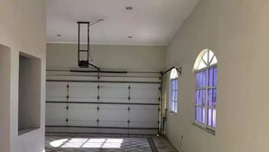 A spacious room with a tiled floor, a large window with purple-tinted glass, and a ceiling fan. - Casa Cid (Mazatlán)