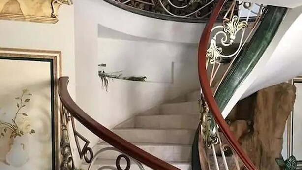 A spiral staircase with ornate metal railings and a wooden handrail. - Casa Cid (Mazatlán)