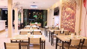 Un restaurante con varias mesas y sillas, una lámpara colgante verde y un mural en la pared.