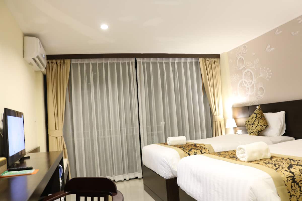 A hotel room with two beds, a desk with a computer, and a chair.