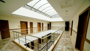 A hotel interior with a central open area, a mezzanine level, and a skylight. - Sriram International (Coimbatore)