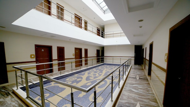 A spacious indoor area with a central open space, multiple doors, and a high ceiling with skylights. - Sriram International (Coimbatore)