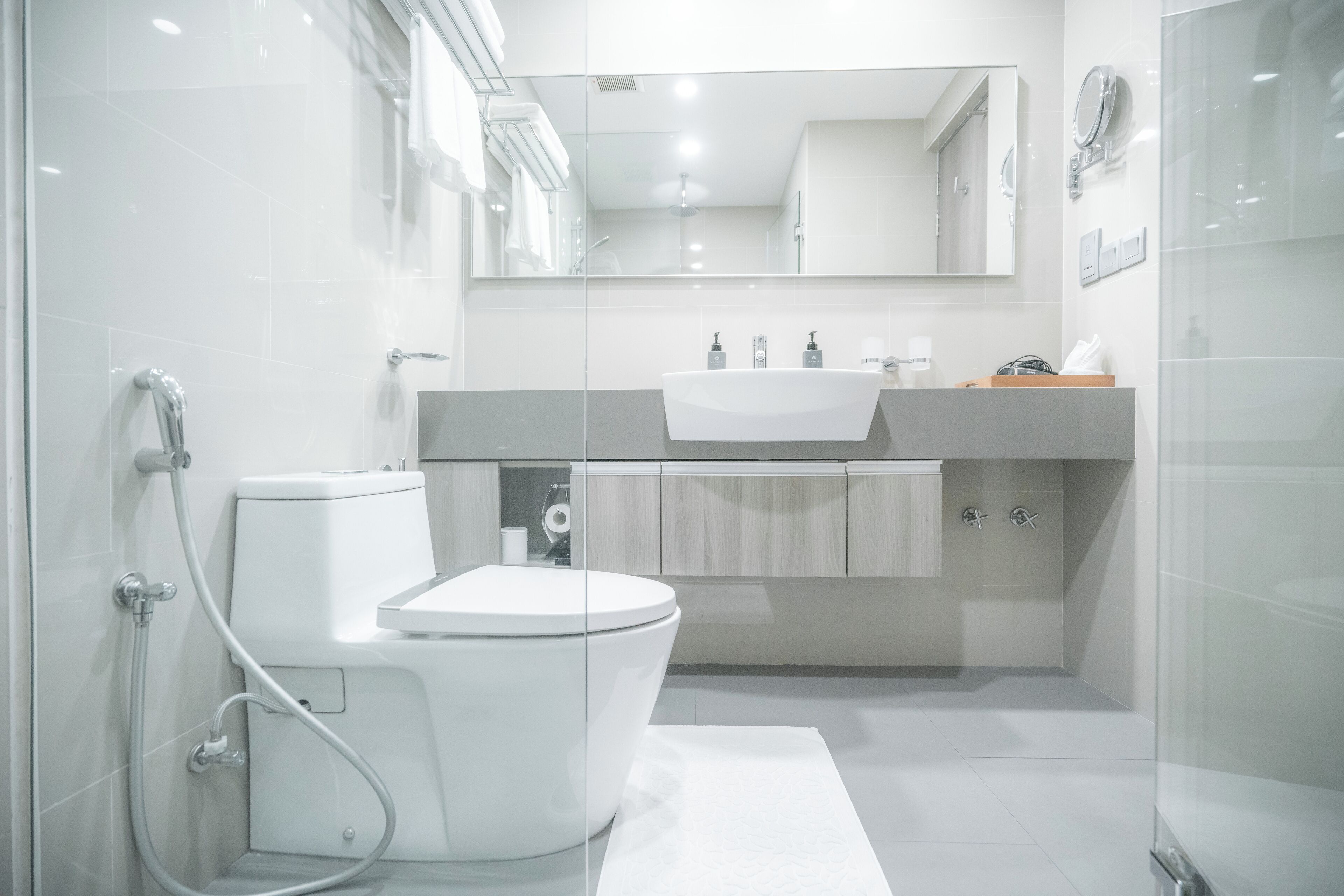A modern bathroom with a glass shower enclosure, a white toilet, a vanity with a sink, and a mirror above the mirror.