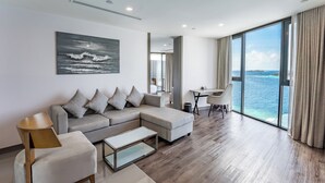 Una sala de estar moderna con un sofá seccional grande, una mesita y vista al océano a través de ventanas amplias.