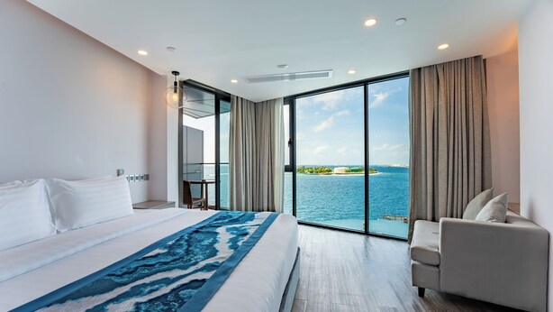 Habitación de hotel moderna con una cama grande, un sofá y vistas al mar.