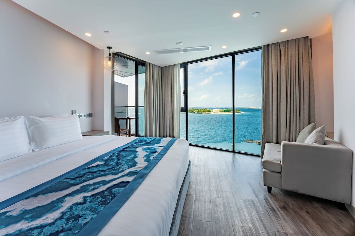 Une chambre d’hôtel moderne avec un grand lit, un canapé et une vue sur la mer.