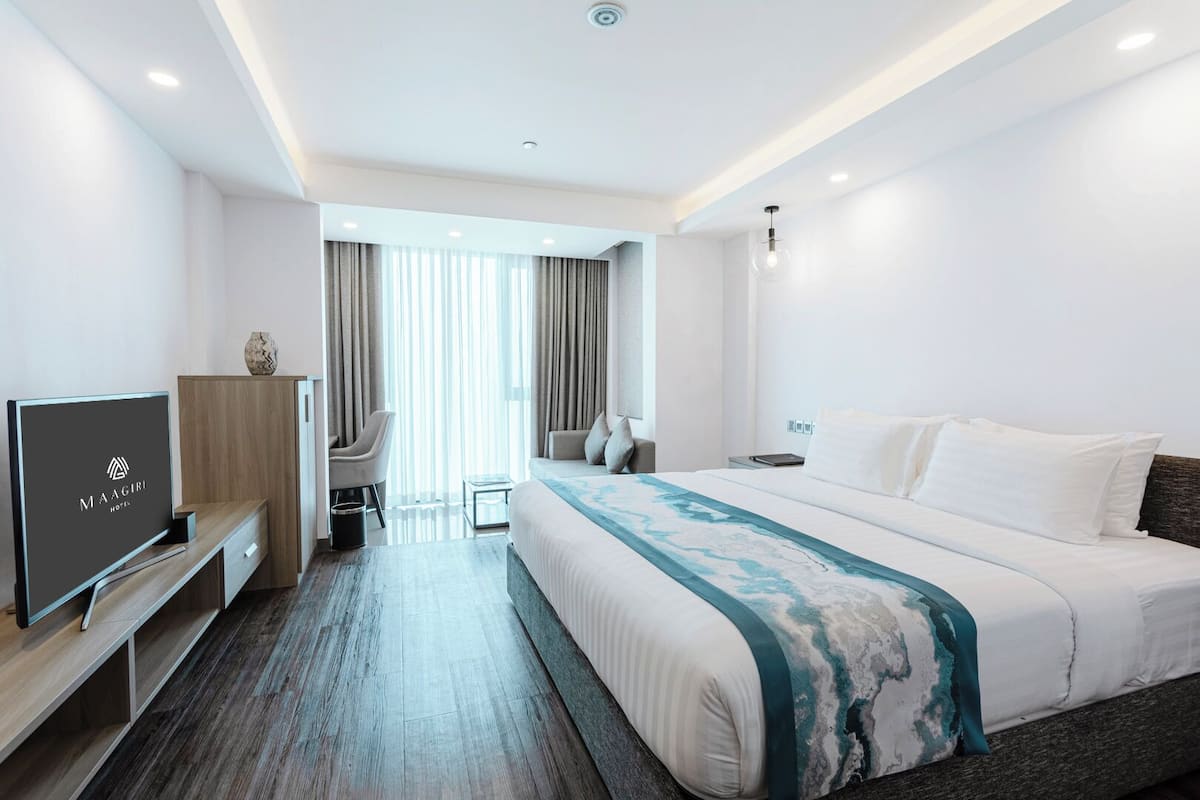 Une chambre d’hôtel moderne équipée d’un grand lit, d’une télévision, d’un bureau et d’une chaise.
