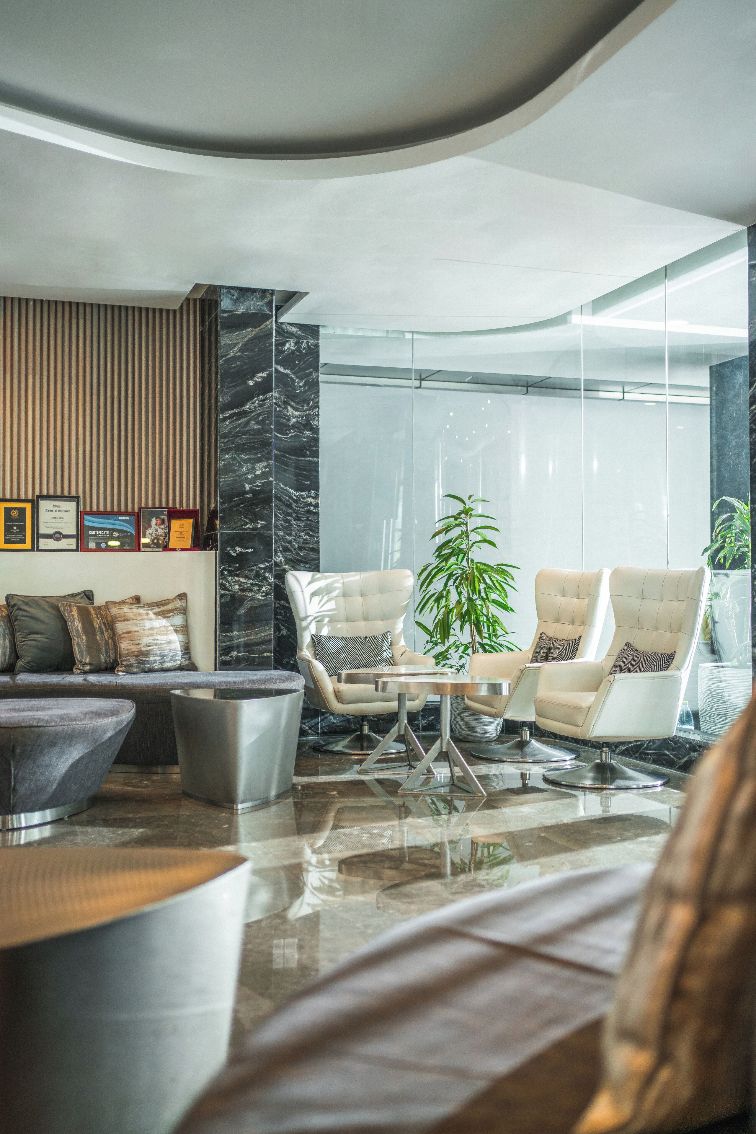 A modern lounge area with a sofa, two armchairs, a coffee table, and a potted plant.