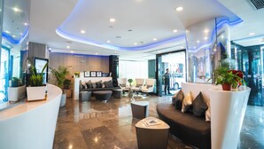 Un moderno vestíbulo de hotel con una recepción, zona de estar y un amplio ventanal.