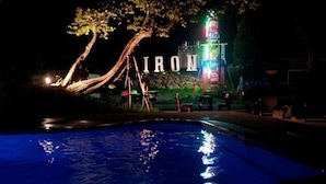 Una piscina con un árbol y un letrero de neón al fondo.