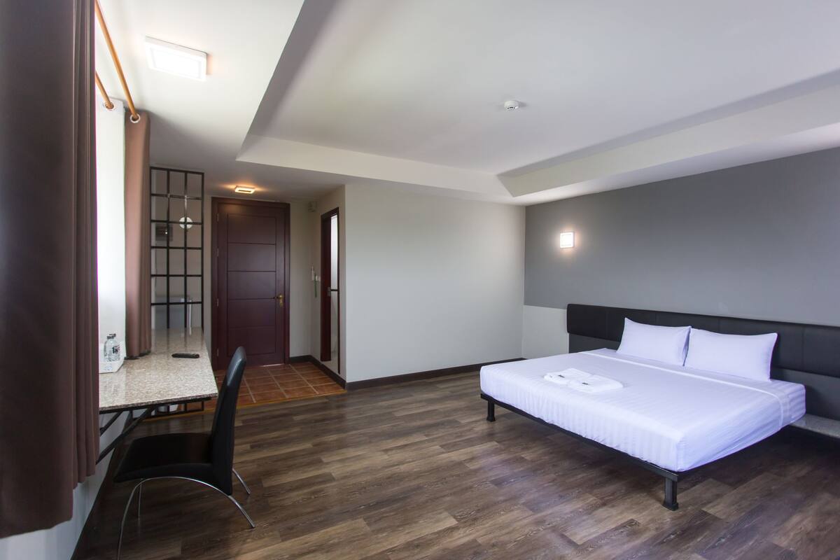 A modern hotel room with a bed, a desk, and a chair.