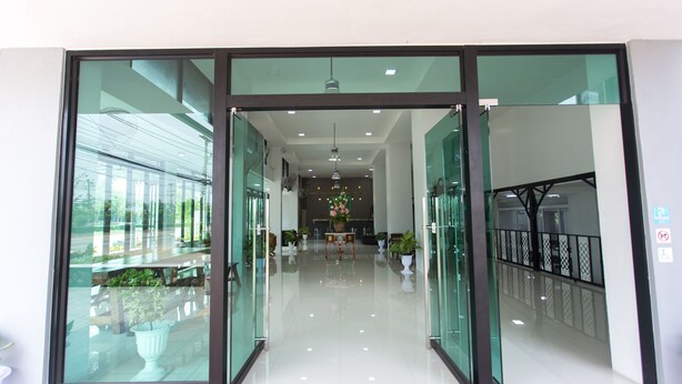 Un moderno vestíbulo de hotel con puertas de cristal, un arreglo floral central y plantas en macetas.