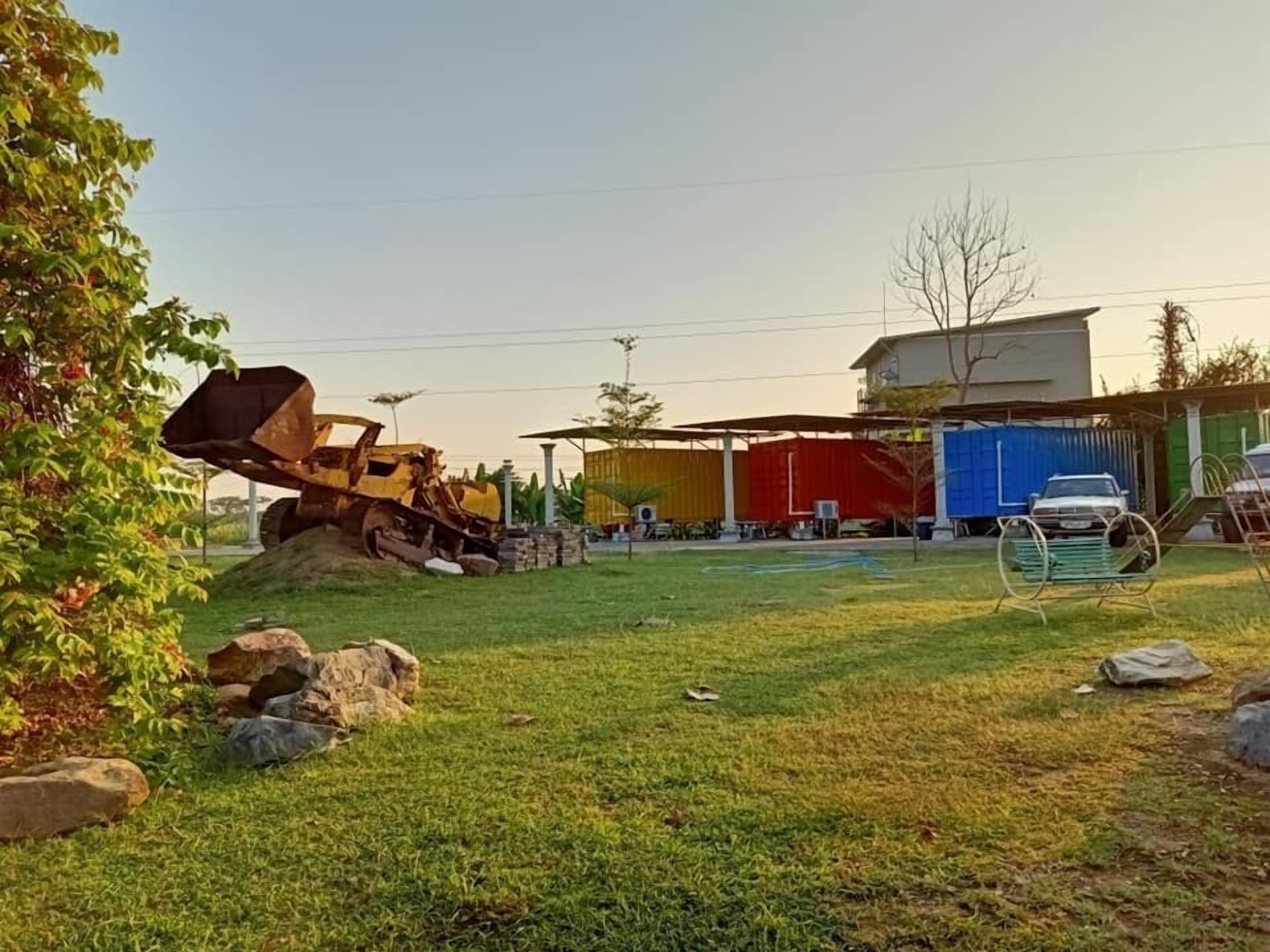 A construction site with a bulldozer, a building with a blue tarp, and a white car parked nearby.
