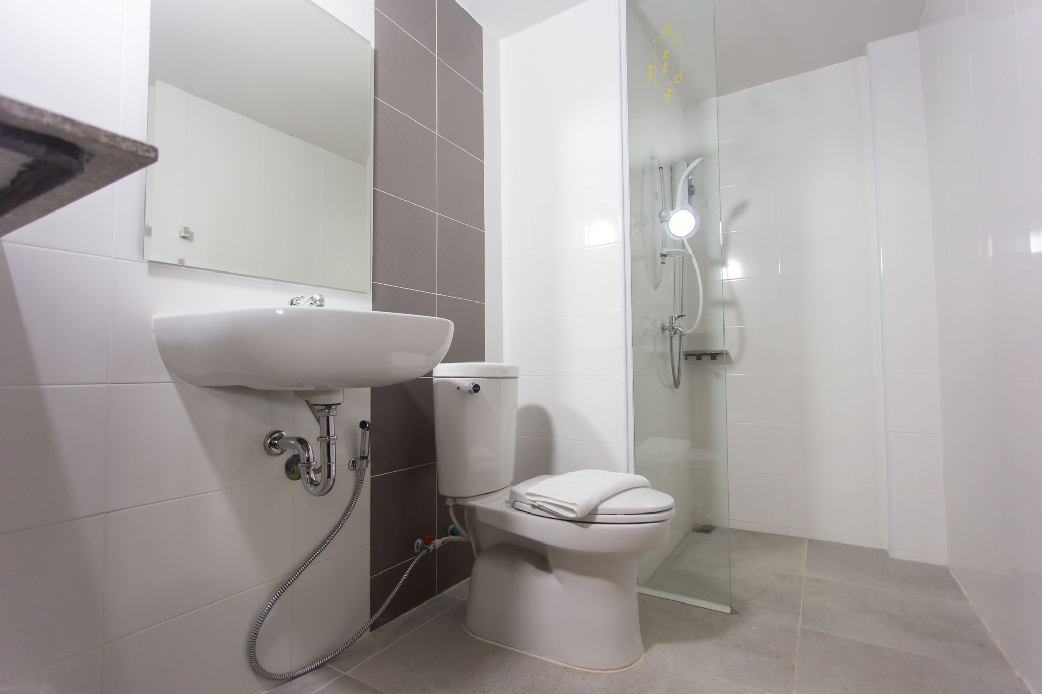 A modern bathroom with a white sink, toilet, and glass-enclosed shower.