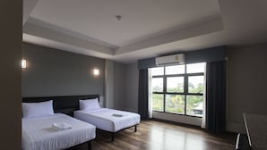 Una habitación de hotel con dos camas, un ventanal con vistas y un equipo de aire acondicionado.