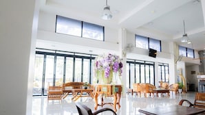 Una habitación amplia con ventanas grandes, muebles de madera y una mesa central con un arreglo floral.