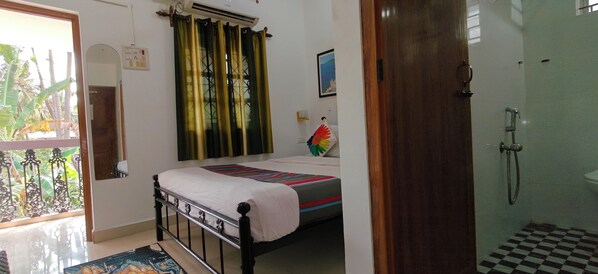 A bedroom with a bed, a shower, and a view of the outdoors. - Hilias Retreat (Canacona)