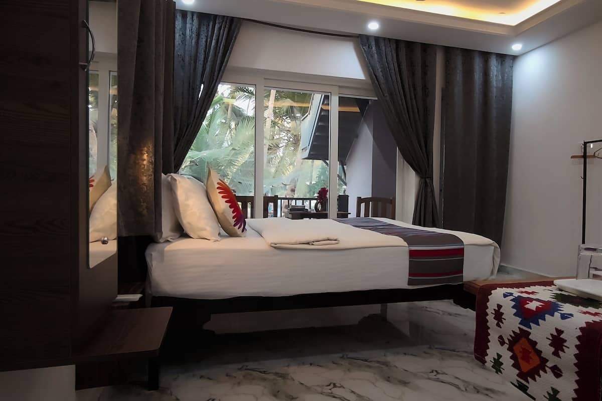 Une chambre à coucher avec un lit, une table de chevet, un miroir, une fenêtre avec des rideaux et une vue sur des palmiers.