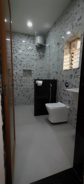 Un baño con inodoro, bidé y lavamanos, con pared decorada y una ventana.
