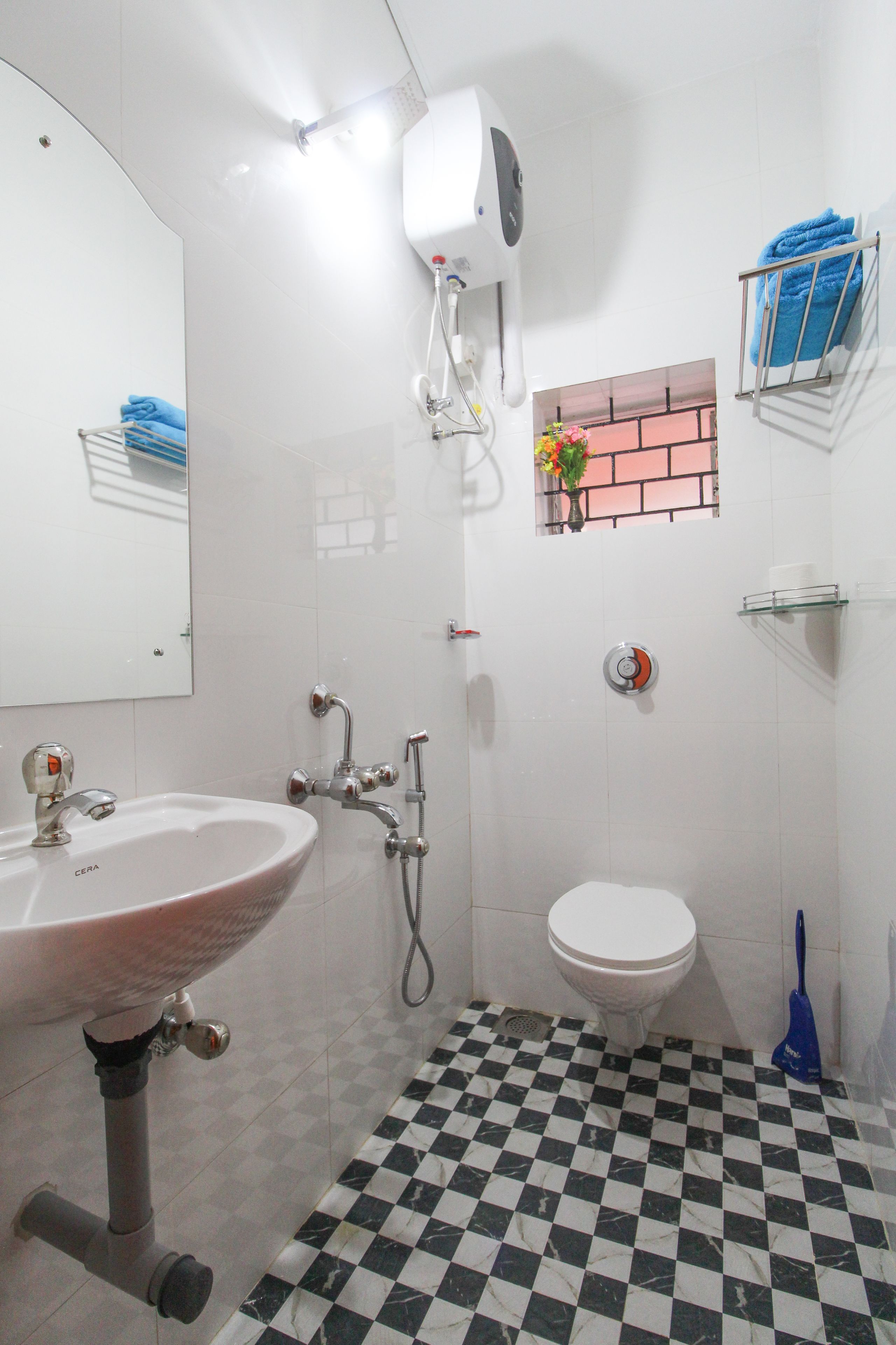 Une salle de bain avec un carrelage à motifs géométriques, un lavabo, des toilettes, une douche et un miroir.