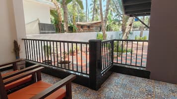 A balcony with a tiled floor, a wooden bench, and a railing.