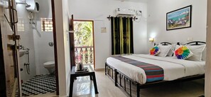 Un dormitorio con cama, ventana con cortinas, un equipo de aire acondicionado y un cuadro en la pared.