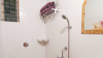 A bathroom with a toilet, a sink, a shower, and a mirror.