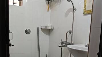 Un baño pequeño y limpio con inodoro, lavamanos, ducha y un trapeador.