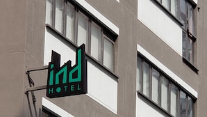 A hotel sign with a modern design, featuring a logo and the word "HOTEL" on a building facade with multiple windows. - IND Hotel (Kowloon)