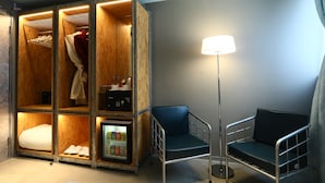 A hotel room with a large walk-in closet, a bedside table with a lamp, and a blue chair. - IND Hotel (Kowloon)