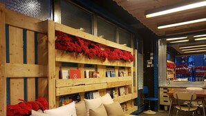 A cozy interior with a wooden bookshelf, a bench with cushions, and a dining area with chairs and a table. - IND Hotel (Kowloon)