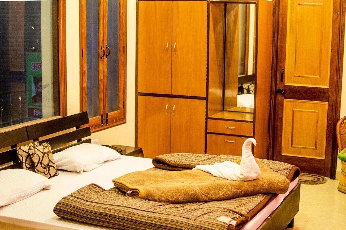 A hotel room with a bed, wooden wardrobe, and a mirror.