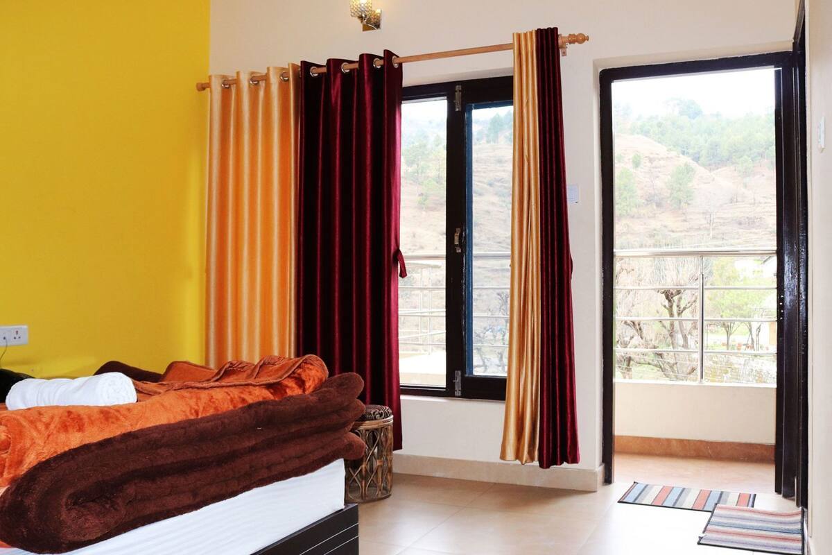 A bedroom with a bed, curtains, a window, and a view of the outdoors.