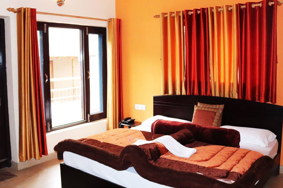 A hotel room with a bed, curtains, a nightstand, and a window.