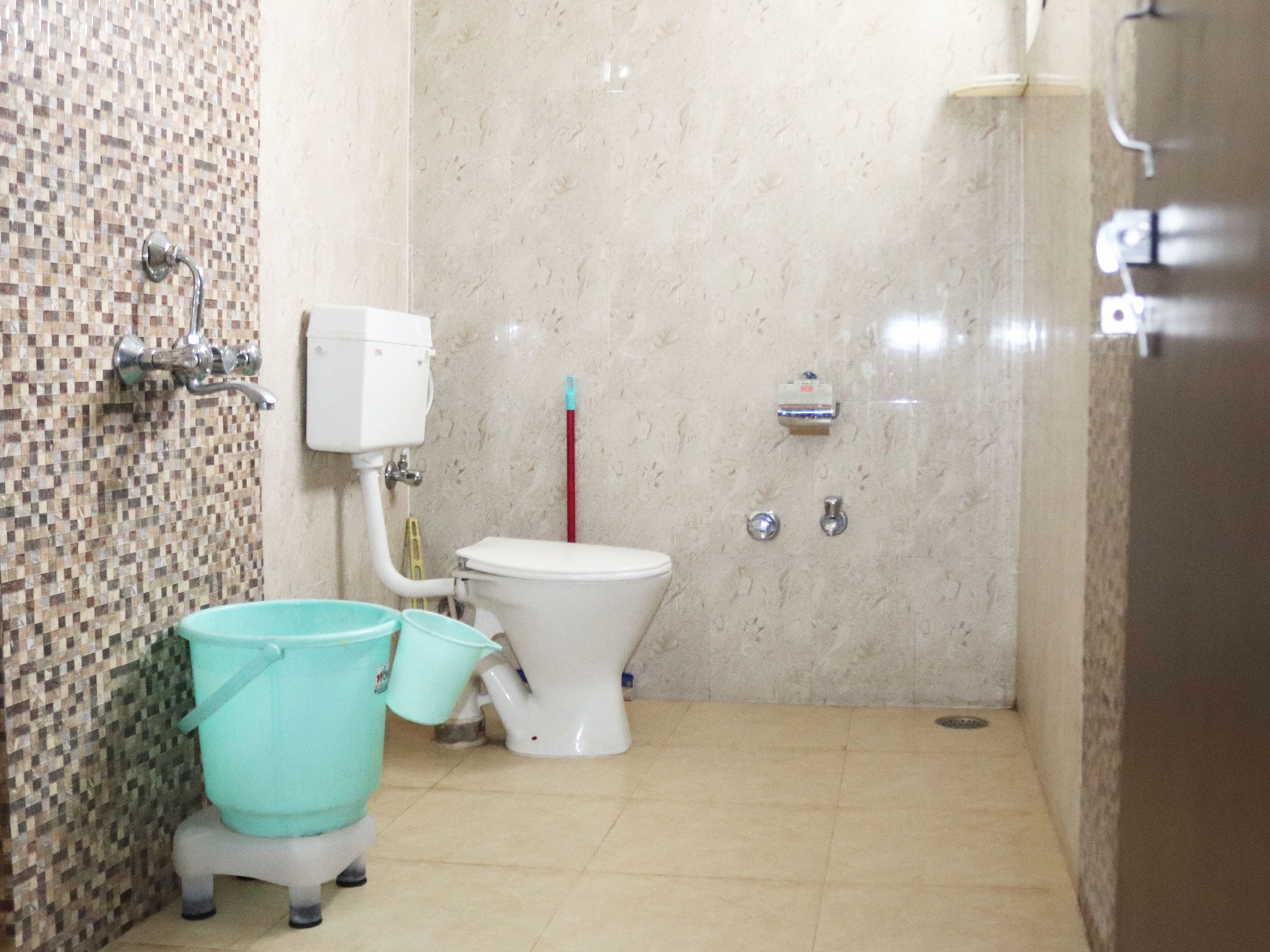 Une salle de bain équipée de toilettes, d’un bidet et d’un seau.
