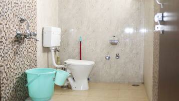 Une salle de bain équipée de toilettes, d’un bidet et d’un seau.