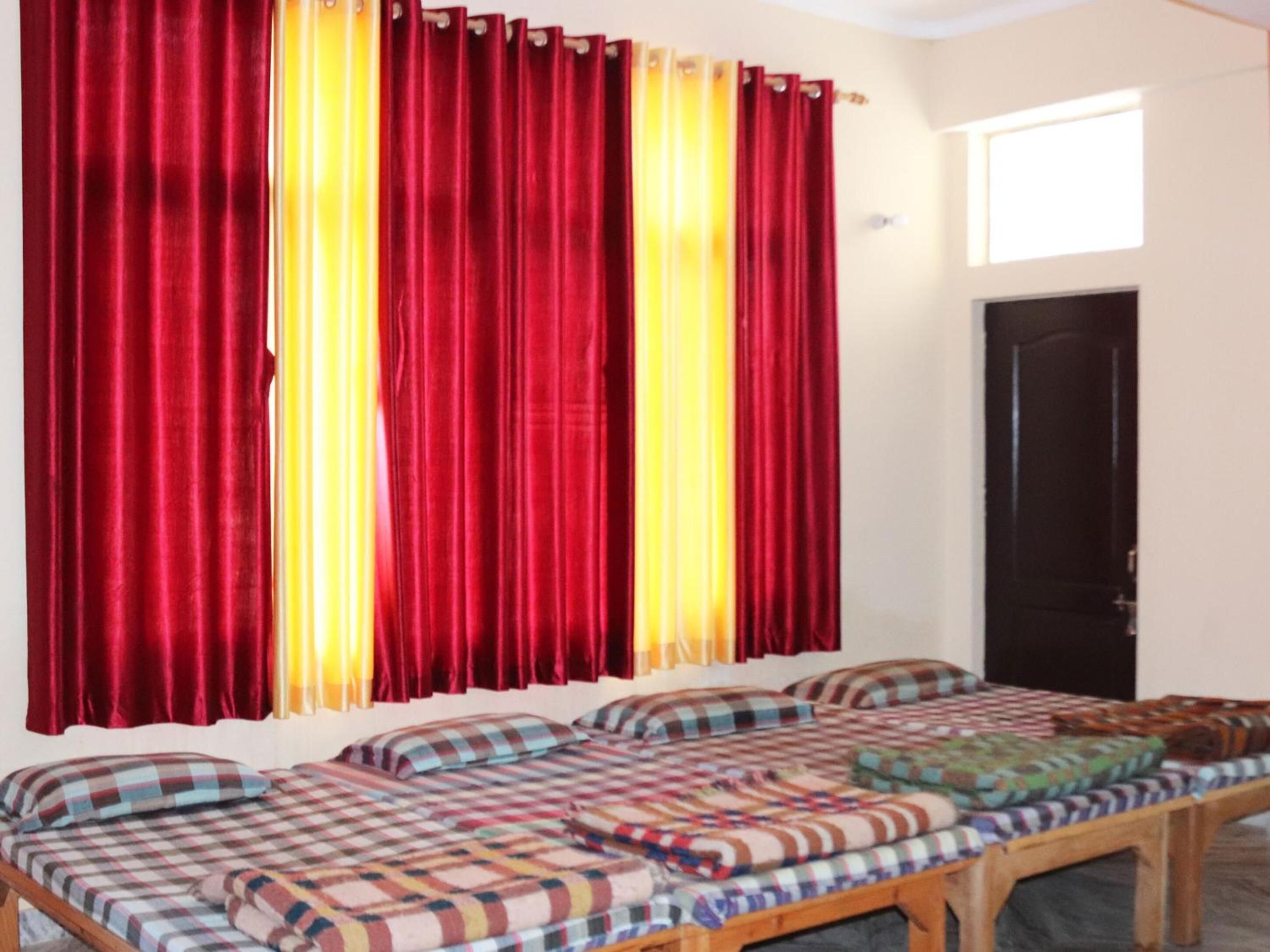 A room with a bed, a window with curtains, and a door.