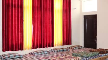 Una habitación con cama, ventana con cortinas y puerta.