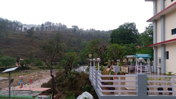 Un hotel de fachada blanca, con un área de estar al aire libre cubierta y vistas a un paisaje montañoso.