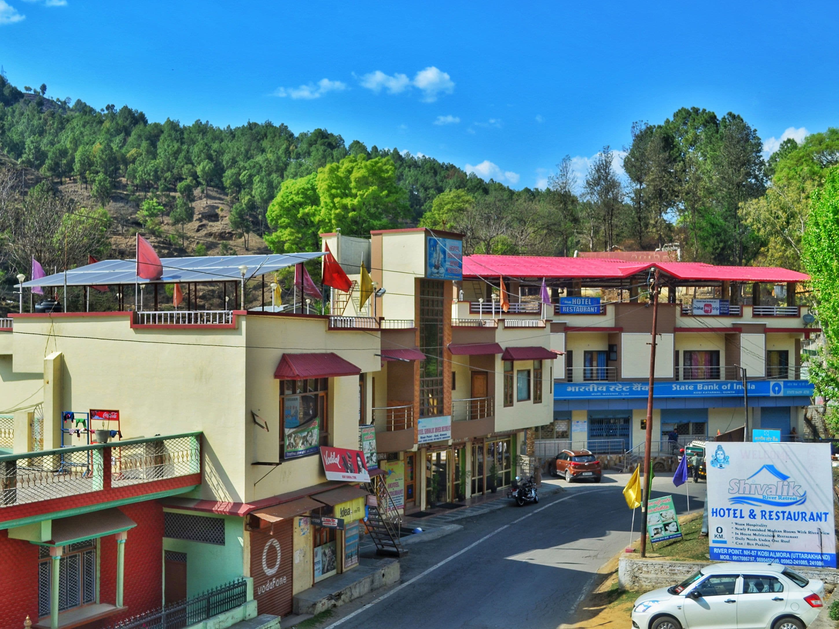 Un hotel con varios pisos, techo rojo y un cartel que anuncia servicios de hotel y restaurante.