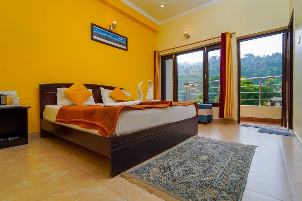 A bedroom with a bed, a nightstand, a framed picture, and a view of greenery through the window.
