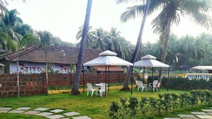 A courtyard with outdoor seating, palm trees, and a building with 'OTITS' signage. - La Vega Resort (Morjim)